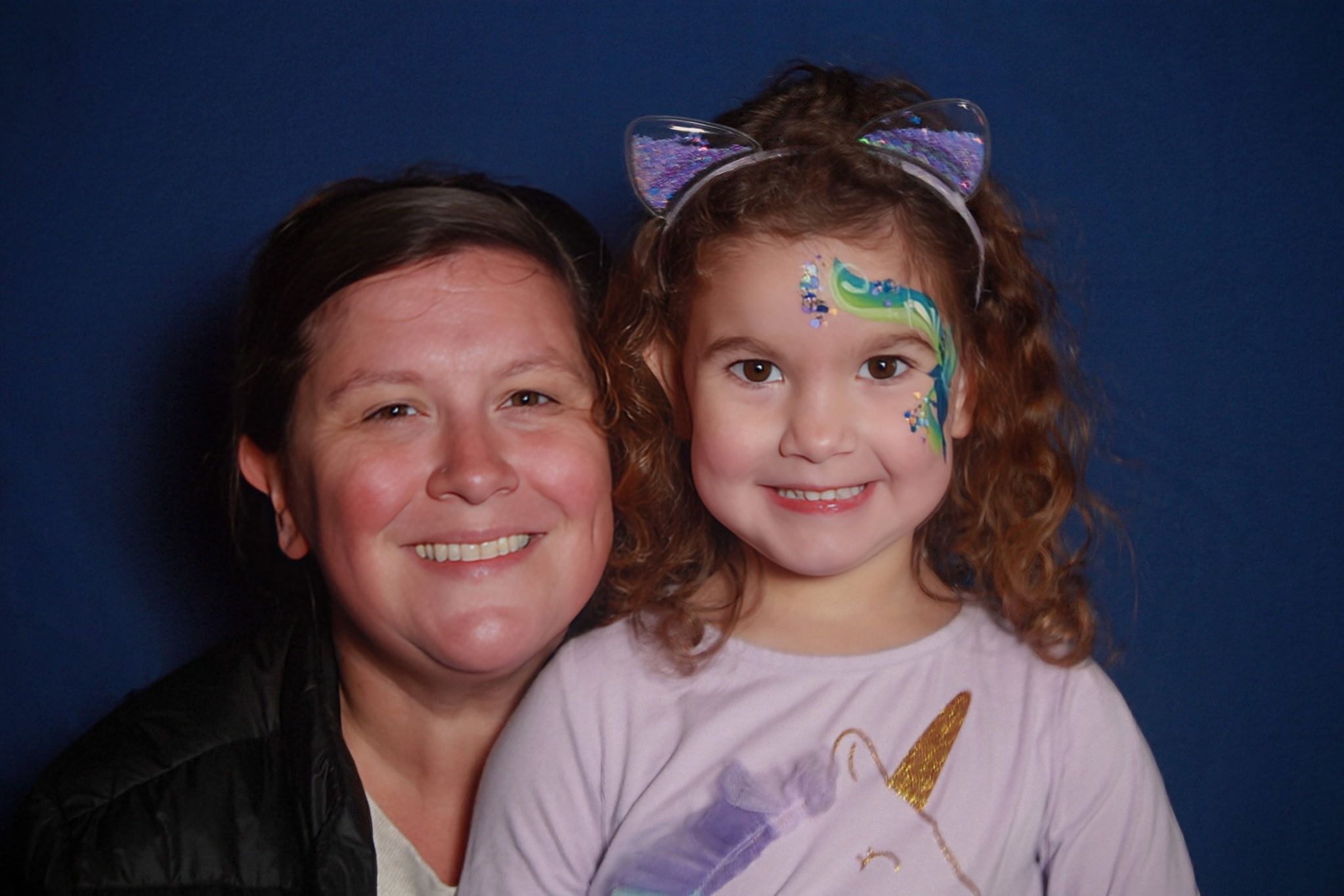 mother and daughter with face paint and a unicorn shirt smiling