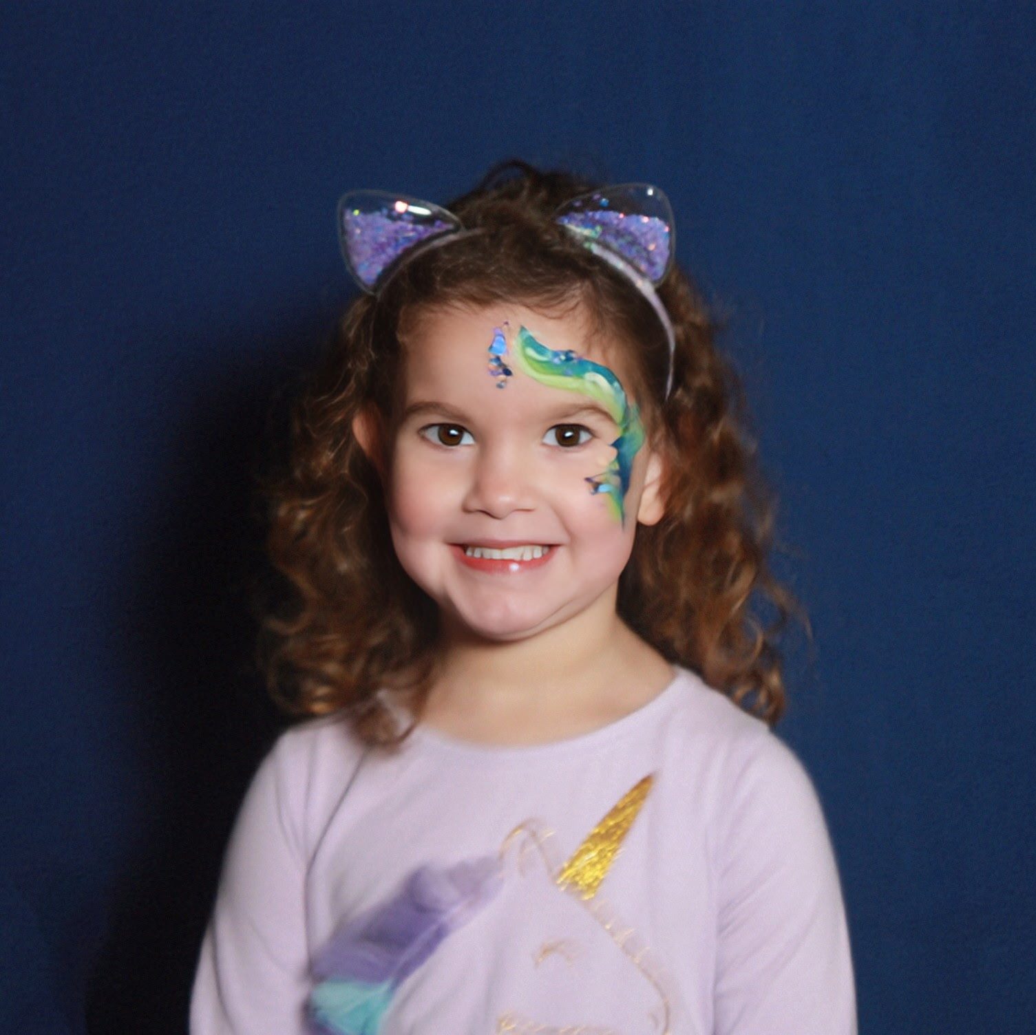 girl with face paint and a unicorn shirt smiling